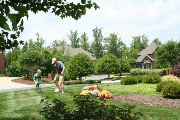 Father and son playing soccer on their recently maintained landscape in Charlotte